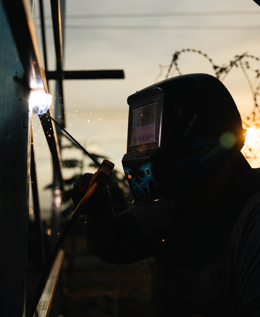 Welder finishing a job at sunset, sparks against the sky